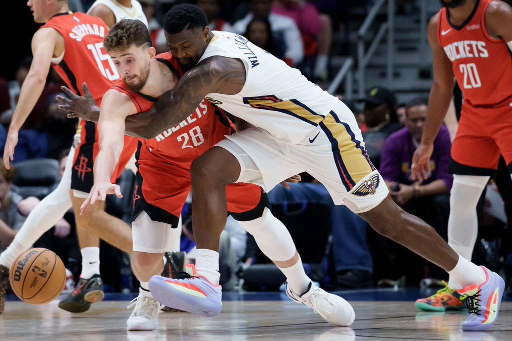Houston Rockets center Alperen Sengun (28) and New Orleans Pelicans forward Zion Williamson, center right, battle for the ball during the first half of an NBA basketball game in New Orleans, Thursday, Dec. 18, 2025. (AP Photo/Matthew Hinton)
