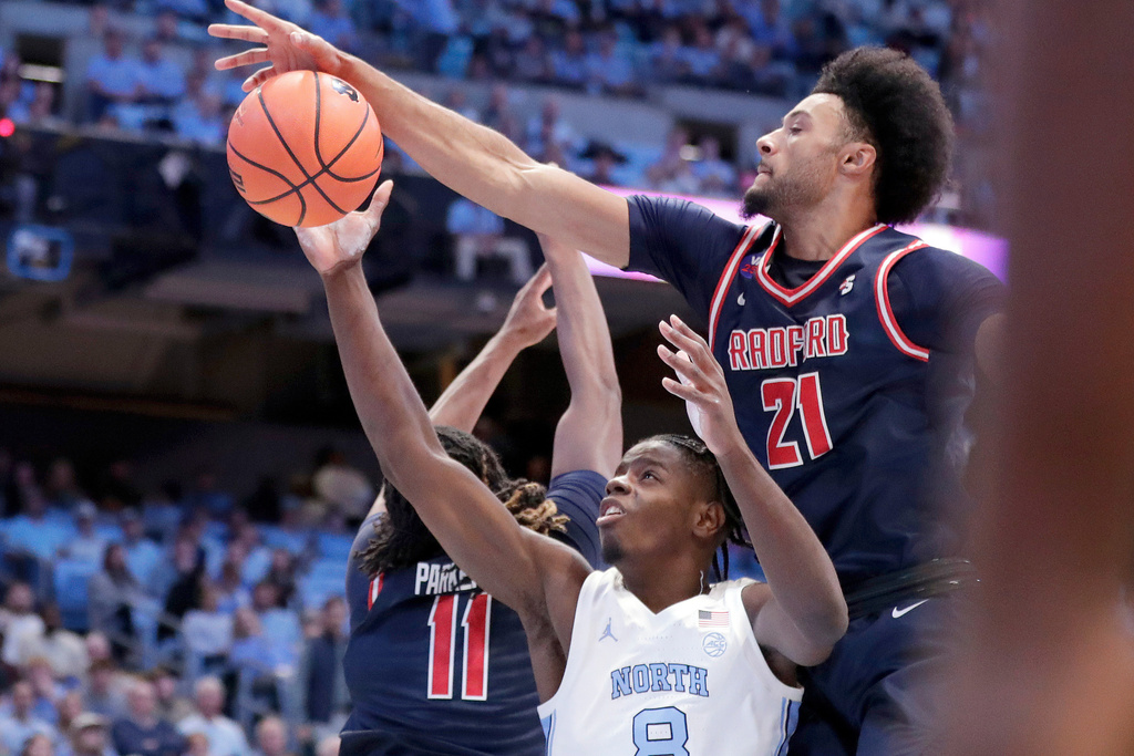 North Carolina forward Caleb Wilson is defended by Radford guard Jr. Dennis Parker (11) and forward Tyson Brown (21) during the first half of an NCAA college basketball game, Tuesday, Nov. 11, 2025, in Chapel Hill, N.C. (AP Photo/Chris Seward)