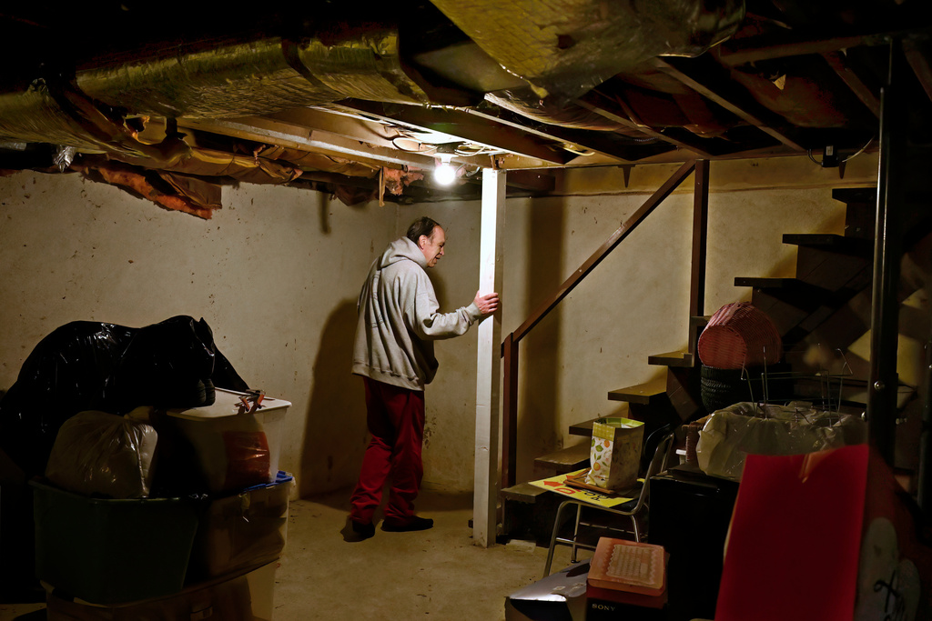 Mark Bain, who is part of the Low Income Home Energy Assistance Program, heads up from the basement to turn down the thermostat of his home in hopes that he will have enough oil to outlast the shutdown, in Bloomfield, Conn., Monday, Oct. 27, 2025. (AP Photo/Jessica Hill)