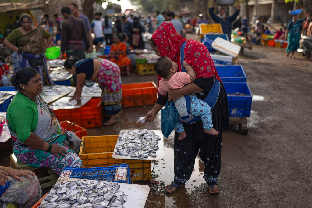 A woman carrying her child checks out fresh fish at at Bhaucha Dhaka in Mumbai, India, Wednesday, April 8, 2026. (AP Photo/Rafiq Maqbool)