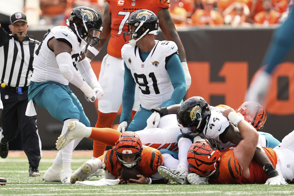 Cincinnati Bengals quarterback Joe Burrow, bottom left, is sacked by Jacksonville Jaguars defensive tackle Arik Armstead (91) during the first half of an NFL football game, Saturday, Sept. 14, 2024, in Cincinnati. (AP Photo/Carolyn Kaster)