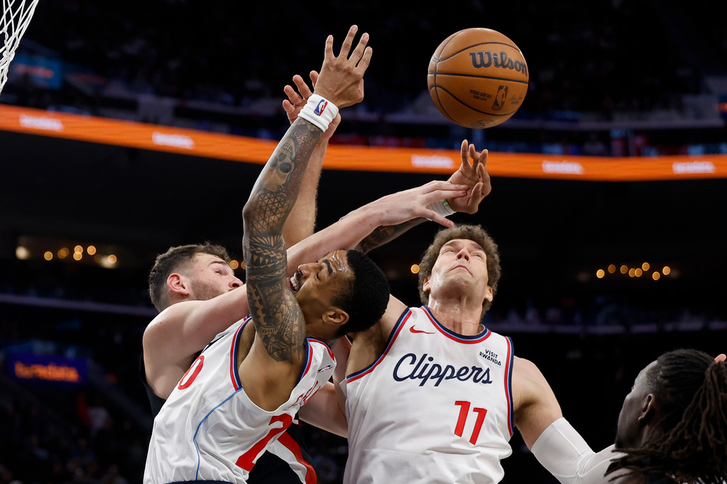 Portland Trail Blazers center Donovan Clingan (23), LA Clippers forward John Collins (20) and LA Clippers center Brook Lopez (11) fight for possession of the ball during the second half of an NBA basketball game Tuesday, March 31, 2026, in Inglewood, Calif. (AP Photo/Caroline Brehman)
