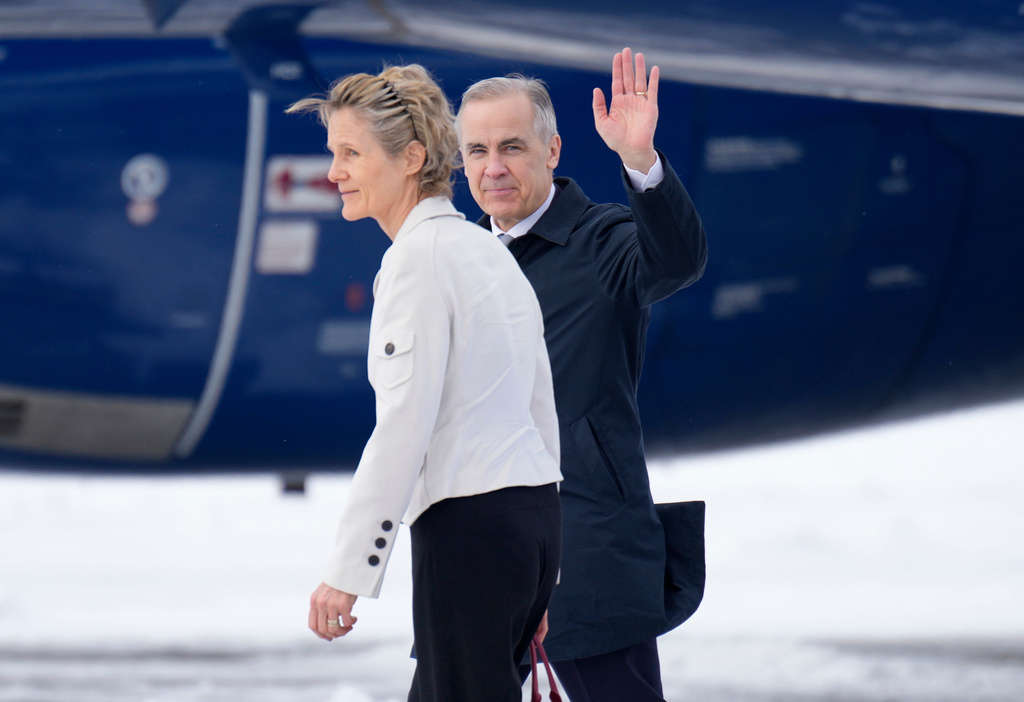 Prime Minister Mark Carney waves as he walks to a government plane with his wife Diana Fox Carney in Ottawa on Thursday, Feb. 26, 2026. (Adrian Wyld/The Canadian Press via AP)