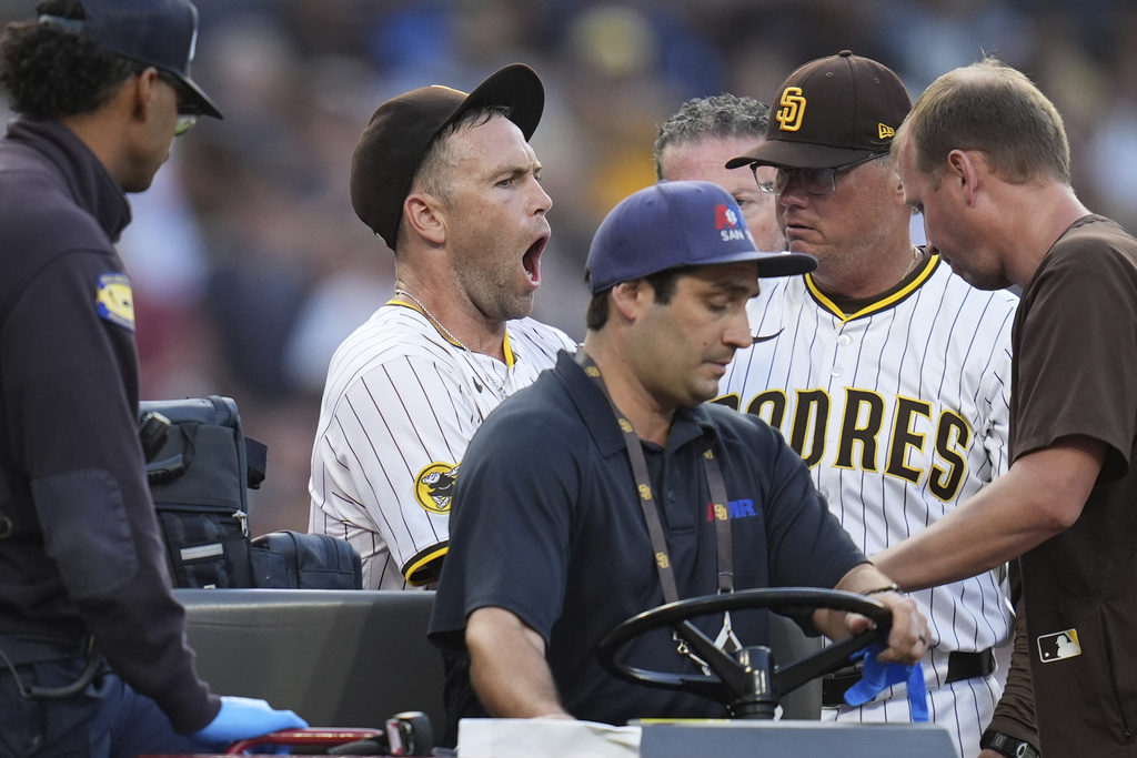 San Diego Padres relief pitcher Jason Adam, second from left, reacts alongside manager Mike Shildt as he leaves in a cart after falling with an injury during the seventh inning of a baseball game against the Baltimore Orioles Monday, Sept. 1, 2025, in San Diego. (AP Photo/Gregory Bull)
