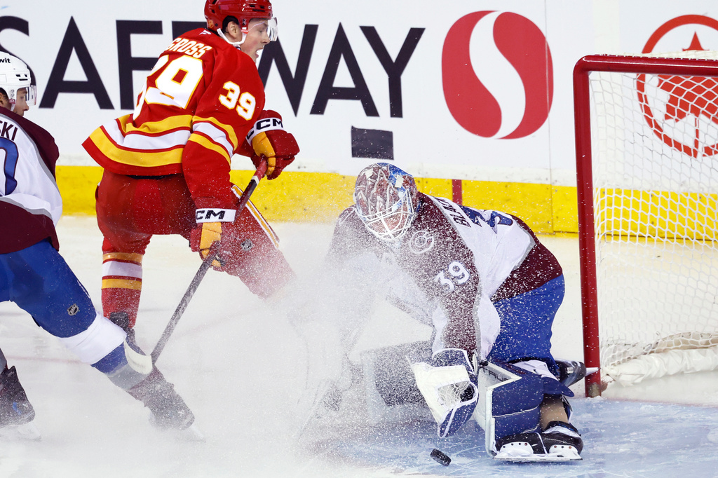 Colorado Avalanche goalie Mackenzie Blackwood, right, makes a save against Calgary Flames' Tyson Gross, center left, during the second period of an NHL hockey game in Calgary, Alberta, Tuesday, April 14, 2026. (Larry MacDougal/The Canadian Press via AP)