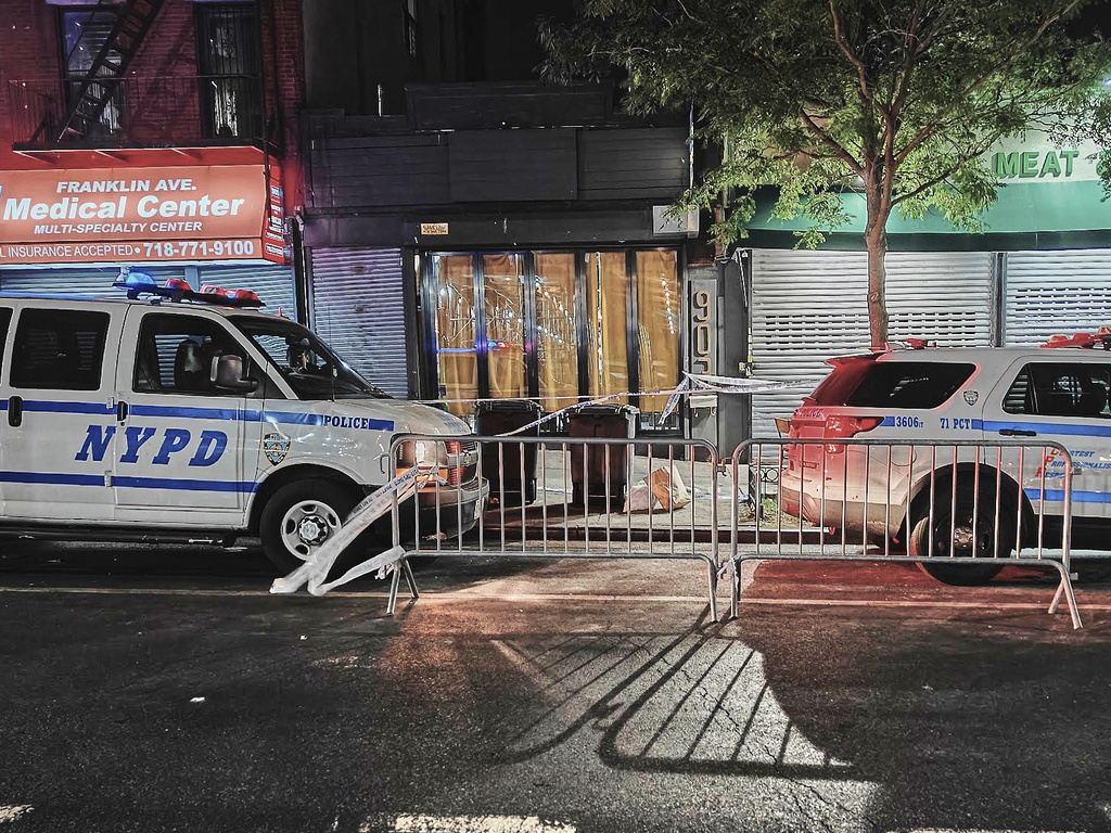 A pair of New York City Police Department vehicles secure the entrance to the Taste of the City Lounge, center, where a shooting took place on Sunday in the Brooklyn borough of New York, Monday, Aug. 18, 2025. (AP Photo/Julie Walker)