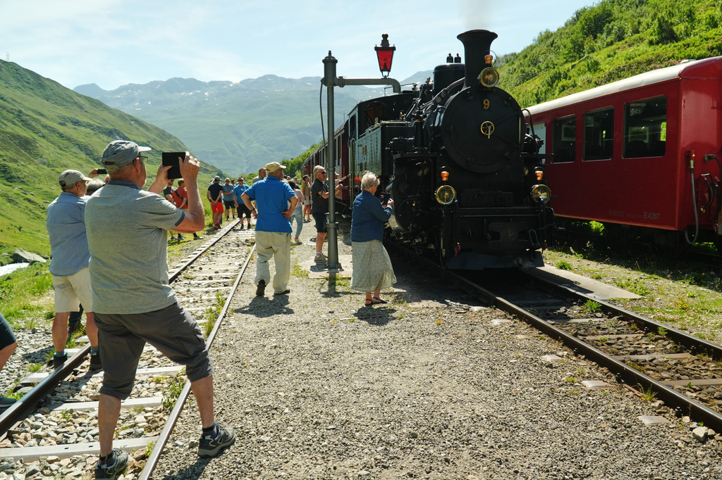 Passengers take photos during a train stop to refill the locomotive with water at Tiefenbach station near Realp, Switzerland, Friday, June 26, 2026. (AP Photo/Niccolo Lupone)