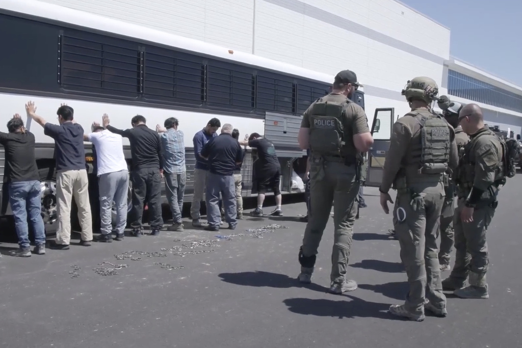 This image from video provided by U.S. Immigration and Customs Enforcement via DVIDS shows manufacturing plant employees waiting to have their legs shackled at the Hyundai Motor Group’s electric vehicle plant, Thursday, Sept. 4, 2025, in Ellabell, Ga. (Corey Bullard/U.S. Immigration and Customs Enforcement via AP)