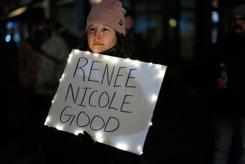 A woman holds a sign for Renee Good, who was fatally shot by an ICE officer in Minneapolis earlier in the week, as people gather outside the U.S. Immigration and Customs Enforcement facility Friday, Jan. 9, 2026, in Portland, Ore. (AP Photo/Jenny Kane)
