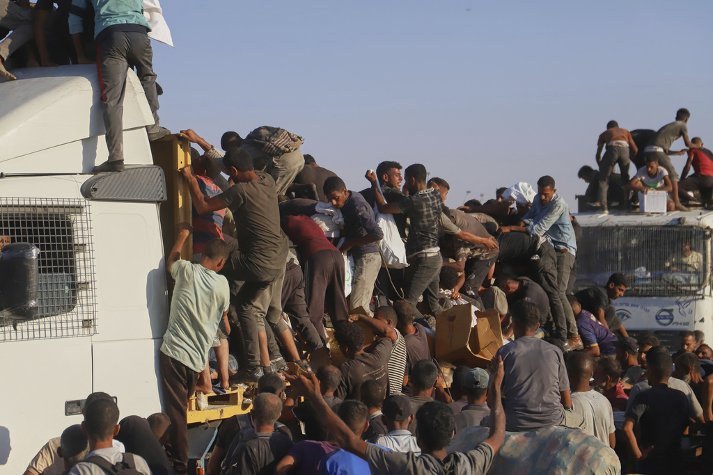 FILE - Palestinians struggle to get food and humanitarian aid from the back of a truck as it moves along the Morag corridor near Rafah, in the southern Gaza Strip, Monday, Aug. 4, 2025. (AP Photo/Mariam Dagga, File)