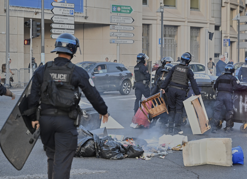 French police walk through burning waste as they try to disperse protesters during a gathering of the "Block Everything" movement in Marseille, south of France, Wednesday, Sept. 10, 2025. (AP Photo/Philippe Magoni)