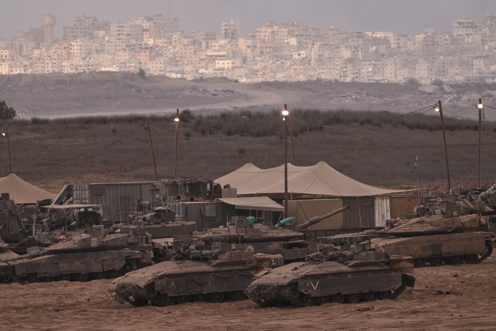 Israeli tanks are parked in a staging area near the Israeli-Gaza border, as seen from southern Israel, Thursday, Oct. 9, 2025, following the announcement that Israel and Hamas have agreed to the first phase of a peace plan to pause the fighting. (AP Photo/Ariel Schalit)