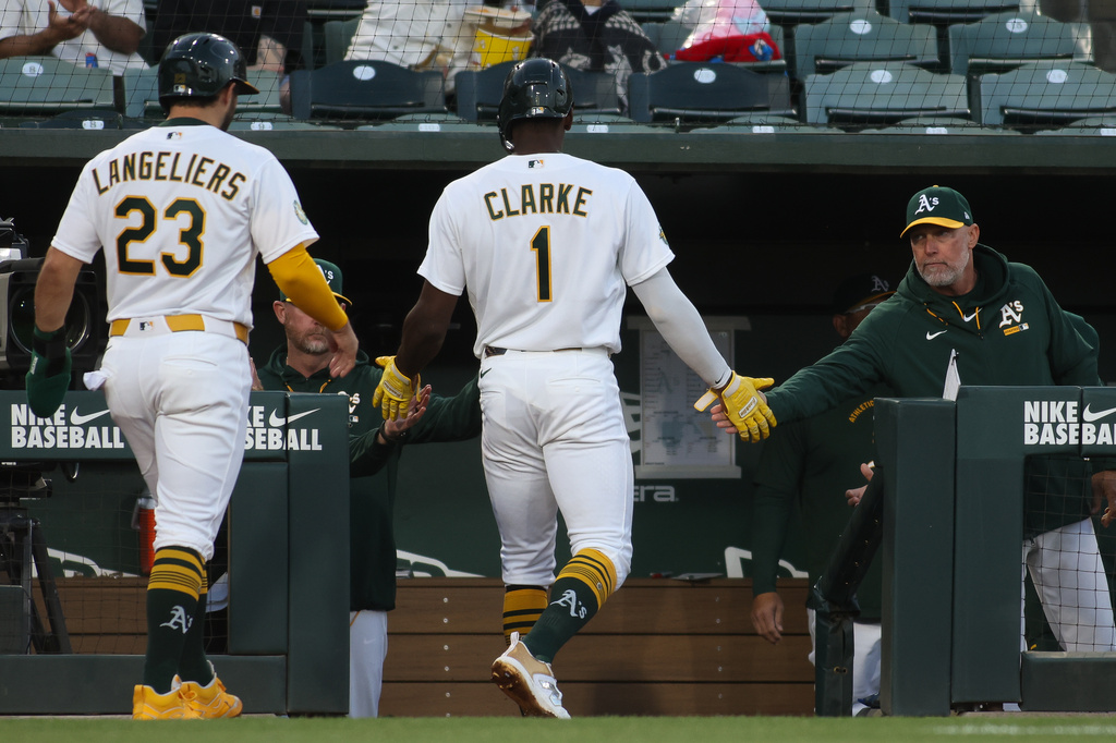 Athletics manager Mark Kotsay, right, congratulates Denzel Clarke (1) after scoring a run during the third inning of a baseball game against the Texas Rangers, Tuesday, April 14, 2026, in West Sacramento, Calif. (AP Photo/Scott Marshall)
