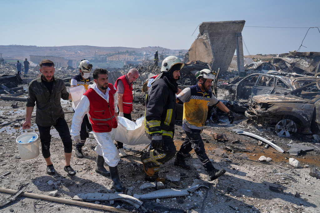 Civil defense workers and a firefighter remove a body from the site of an explosion at what Syria's Defense Ministry said was a warehouse used for the temporary storage of weapons near Sarmada, in Idlib province, Syria, Wednesday, Sept. 9, 2026. (AP Photo/Omar Albam)