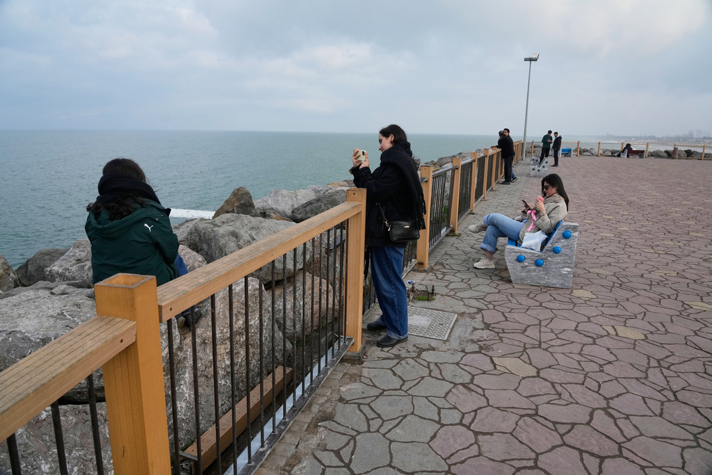 People enjoy their time at the beach of the southern coast of the Caspian Sea outside the port city of Bandar Anzali, Iran, Tuesday, Dec. 23, 2025. (AP Photo/Vahid Salemi)