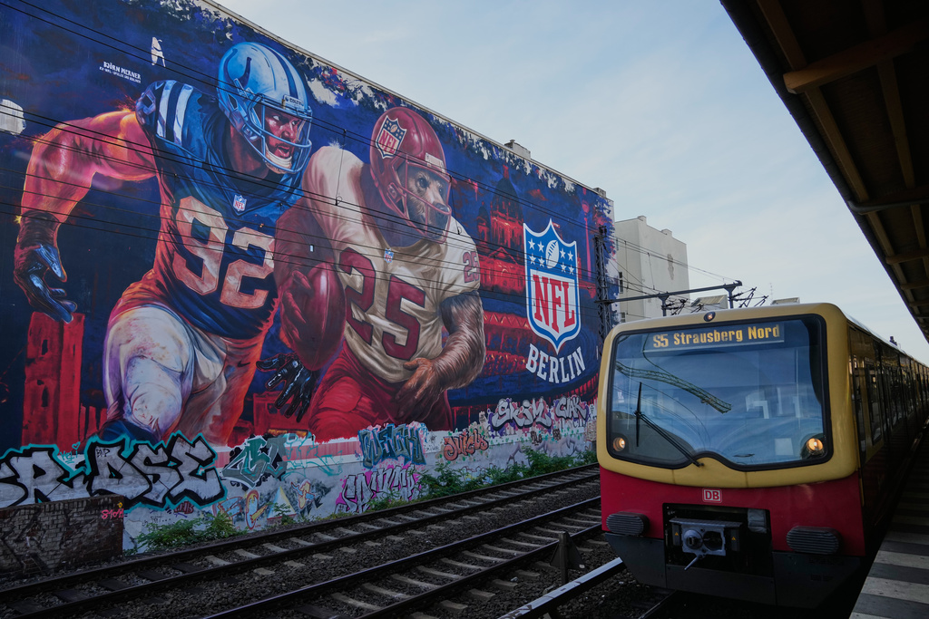 A regional train passes a giant NFL mural by artist Fix77 ahead of the football match between Indianapolis Colts and Atlanta Falcons in Berlin, Wednesday, Nov. 5, 2025. (AP Photo/Ebrahim Noroozi)