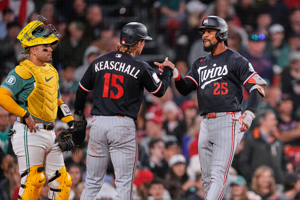 Minnesota Twins' Byron Buxton (25) is congratulated by Luke Keaschall (15) after his two-run home run, as Boston Red Sox catcher Carlos Narváez waits for play to continue, during the seventh inning of a baseball game against the Boston Red Sox, Friday, May 22, 2026, in Boston. (AP Photo/Charles Krupa)