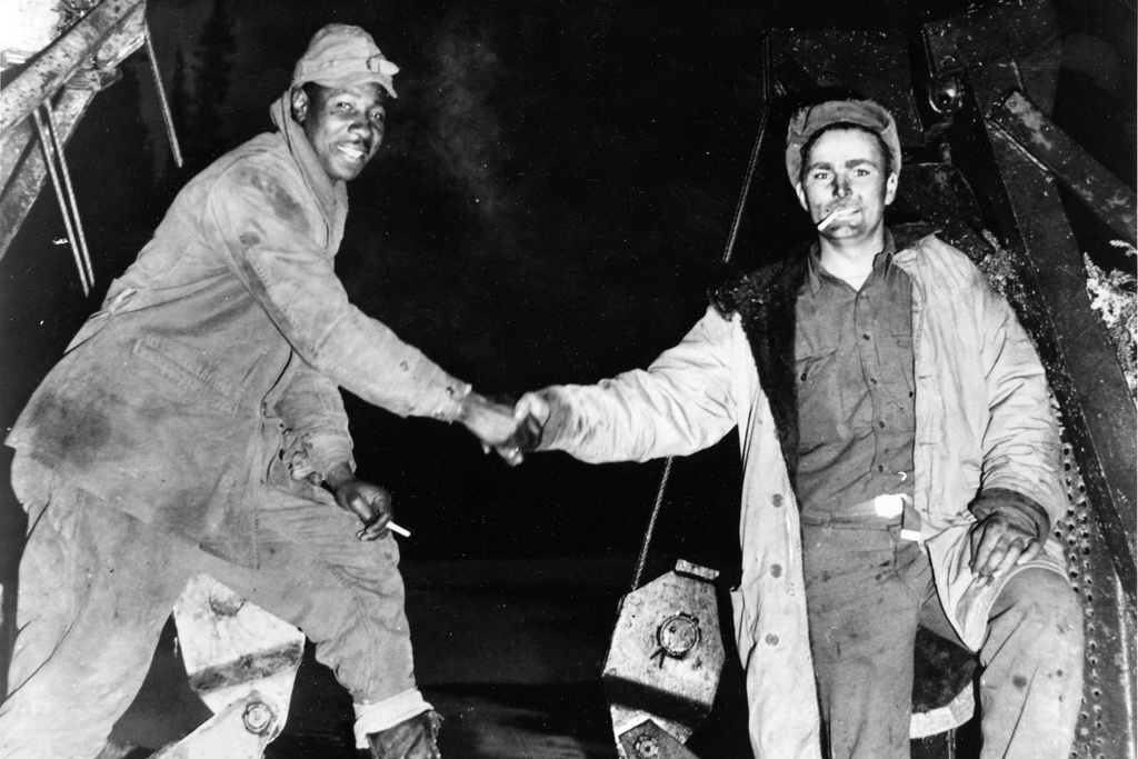 FILE - This Oct. 25, 1942, photo provided by the U.S. Army Corps of Engineers Office of History, shows Corporal Refines Slims, Jr., left, and Private Alfred Jalufka shaking hands at the, "Meeting of Bulldozers," for the ALCAN Highway in the Yukon Territory in Beaver Creek, Alaska. (U.S. Army Corps of Engineers Office of History via AP, File)