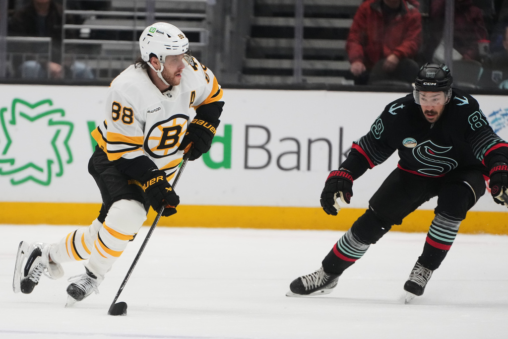 Boston Bruins right wing David Pastrnak moves the puck against Seattle Kraken center Frederick Gaudreau, right, during the third period of an NHL hockey game Tuesday, Jan. 6, 2026, in Seattle. (AP Photo/Lindsey Wasson)