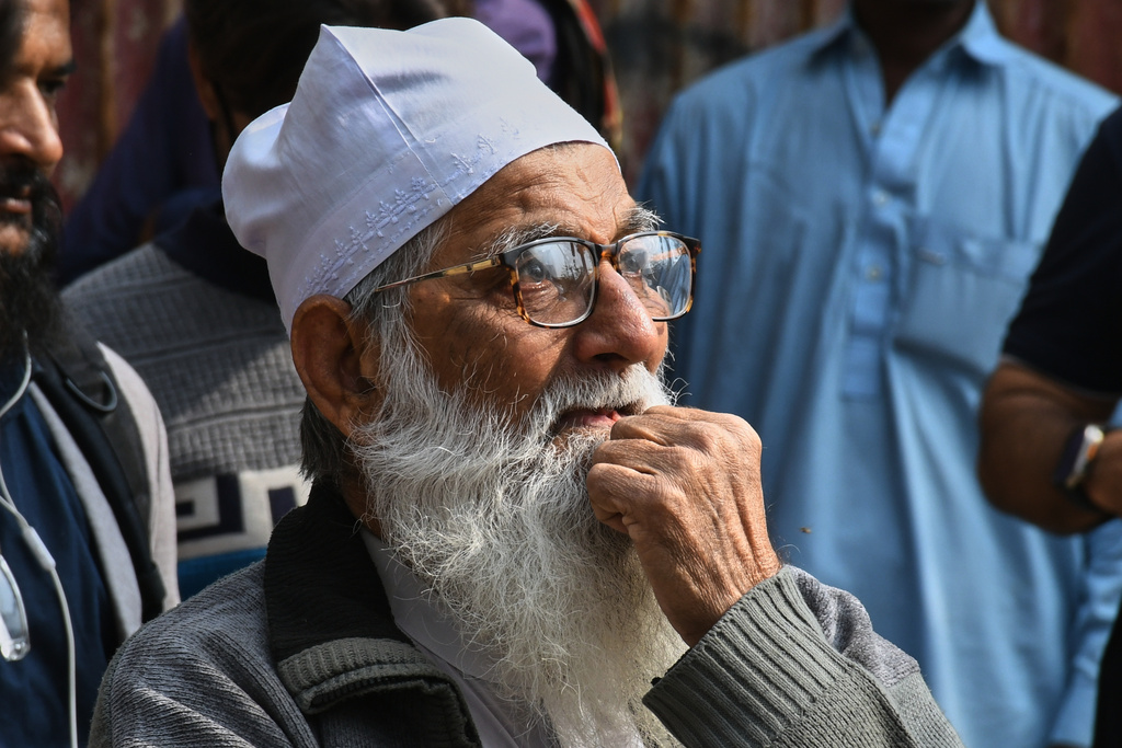 A family member of a missing person waits near the site of a burnt building of a multistory shopping plaza following a massive fire in Karachi, Pakistan, Monday, Jan. 19, 2026. (AP Photo/Ali Raza)