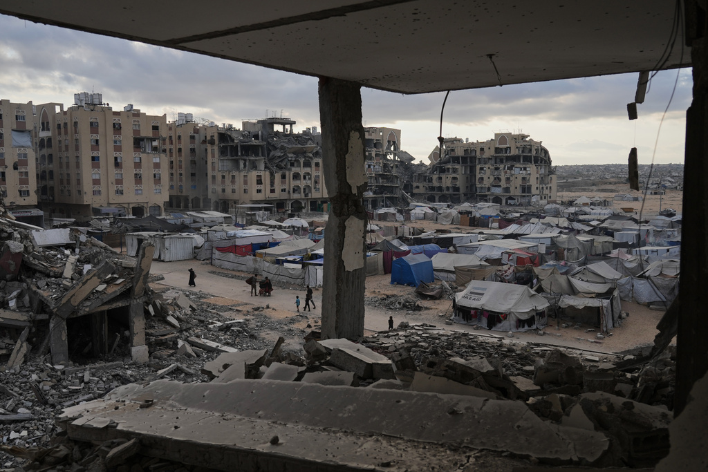 A tent camp for displaced Palestinians sits adjacent to destroyed homes and buildings in Khan Younis, Gaza Strip, Saturday, Oct. 18, 2025. (AP Photo/Jehad Alshrafi)