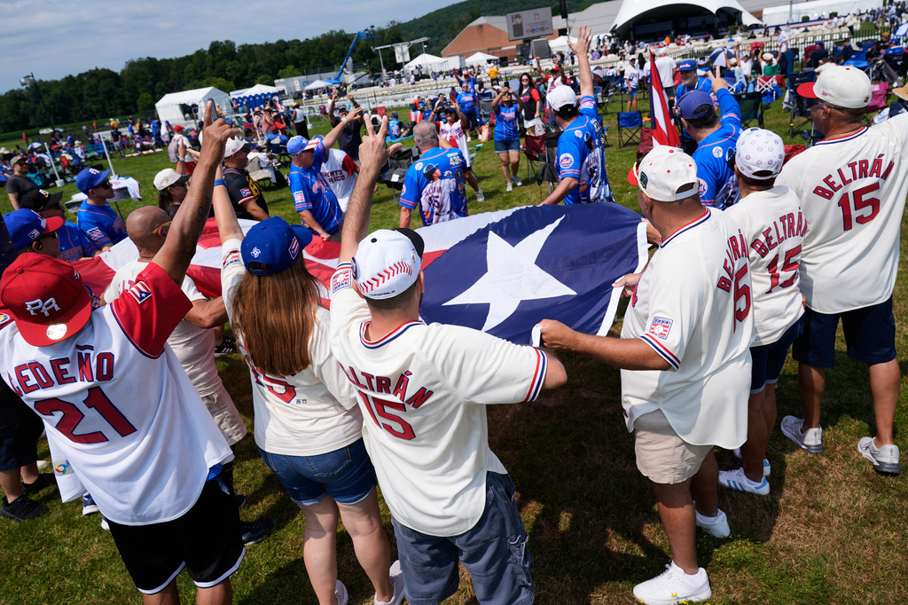 Puerto Rico and Carlos Beltran supporters pose for pictures with a Puerto Rican flag before the start of the Baseball Hall of Fame induction ceremony in Cooperstown, N.Y., Sunday, July 26, 2026. (AP Photo/Seth Wenig)