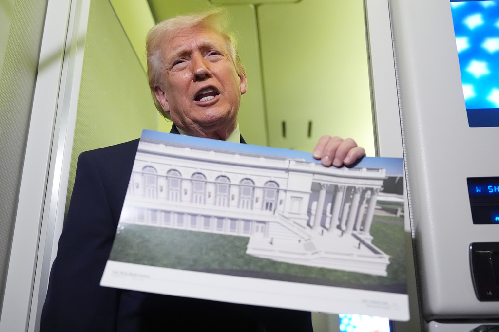 President Donald Trump holds a rendering of the proposed new East Wing of the White House as he speaks to reporters aboard Air Force One en route from West Palm Beach, Fla., to Joint Base Andrews, Md., Sunday, March 29, 2026. (AP Photo/Mark Schiefelbein)