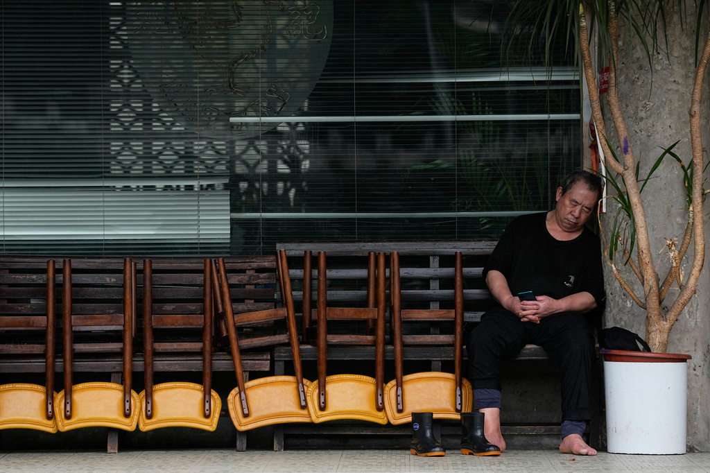 A man takes a nap next to a row of chairs outside a closed restaurant during off-hours in Beijing, China, Wednesday, May 6, 2026. (AP Photo/Andy Wong)