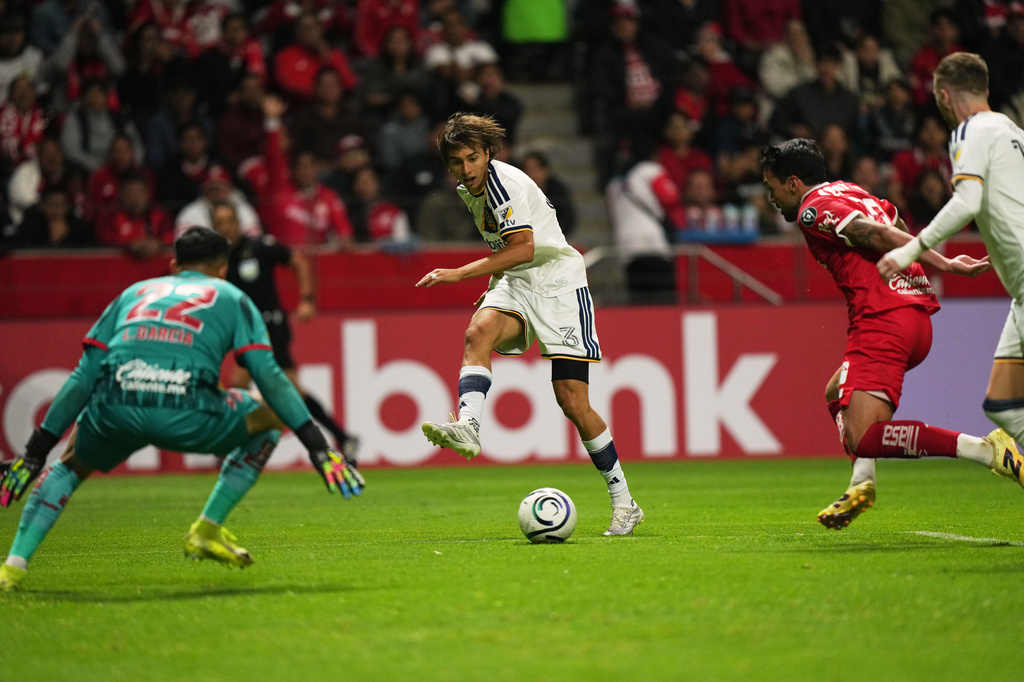 Julian Aude, center, passes the ball to Marco Reus of the United States' LA Galaxy to score against Mexico's Toluca during a CONCACAF Champions Cup quarterfinal first leg soccer match in Toluca, Mexico, Wednesday, April 8, 2026. (AP Photo/Fernando Llano)