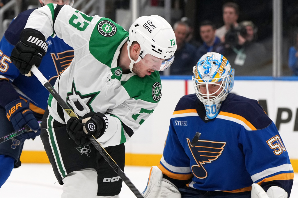 Dallas Stars' Adam Erne (73) and St. Louis Blues goaltender Jordan Binnington keep their eyes on the puck during the third period of an NHL hockey game Saturday, Oct. 18, 2025, in St. Louis. (AP Photo/Jeff Roberson)