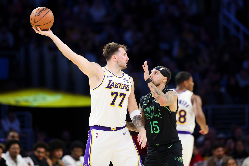 Los Angeles Lakers guard Luka Doncic (77) holds the ball against New Orleans Pelicans guard Jose Alvarado (15) as Los Angeles Lakers forward Rui Hachimura, right, runs during the first half of an NBA basketball game, Sunday, Nov. 30, 2025, in Los Angeles. (AP Photo/Jessie Alcheh)