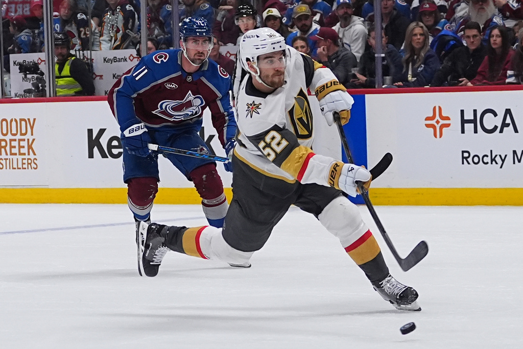 Vegas Golden Knights defenseman Dylan Coghlan, front, shoots the puck for a goal after driving past Colorado Avalanche center Brock Nelson during the second period in Game 1 of the Western Conference finals NHL hockey Stanley Cup playoff series Wednesday, May 20, 2026, in Denver. (AP Photo/David Zalubowski)