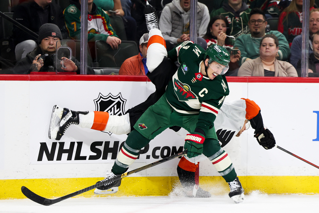 Minnesota Wild defenseman Jared Spurgeon, front, upends Philadelphia Flyers right wing Nikita Grebenkin, behind, during the second period of an NHL hockey game, Thursday, March 12, 2026, in St. Paul, Minn. (AP Photo/Ellen Schmidt)