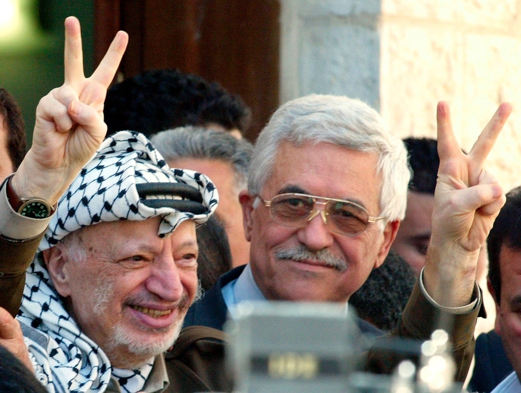 FILE.- Palestinian leader Yasser Arafat makes the victory sign as he leaves the confidence vote session of the Palestinian Legislative Council accompanied by Prime Minister-designate Mahmoud Abbas, right, at his headquarters in the West Bank town of Ramallah Tuesday, April 29, 2003. (AP Photo/Ricardo Mazalan, File)
