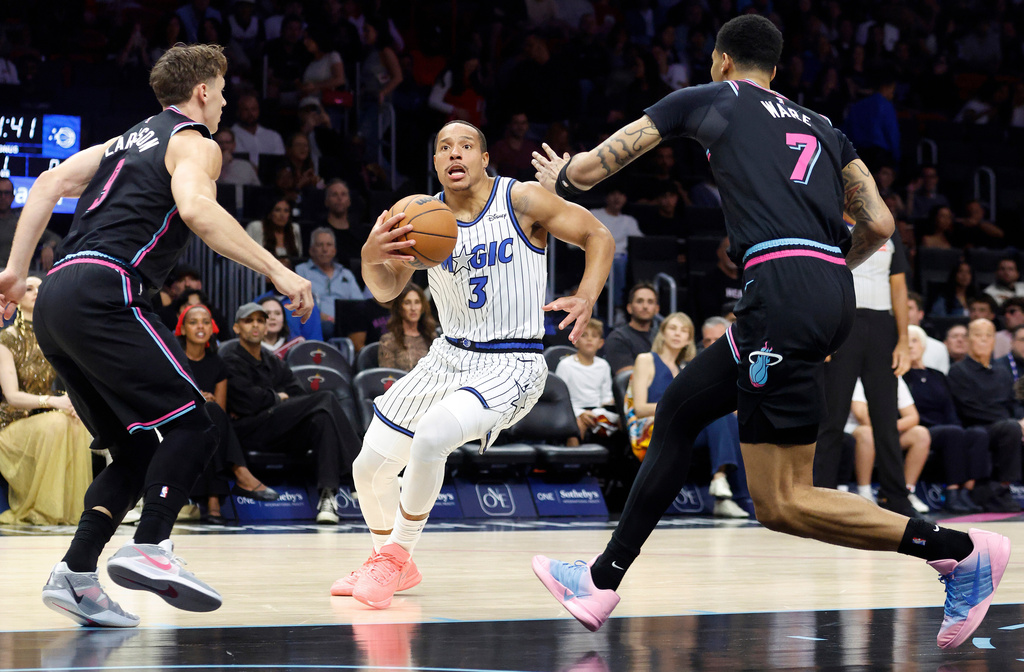 Miami Heat guard Pelle Larsson (9) and Miami Heat Kel'el Ware (7) defend Orlando Magic guard Desmond Bane (3) during the first half of an NBA basketball game in Miami, Saturday, March 14, 2026. (AP Photo/Rhona Wise)