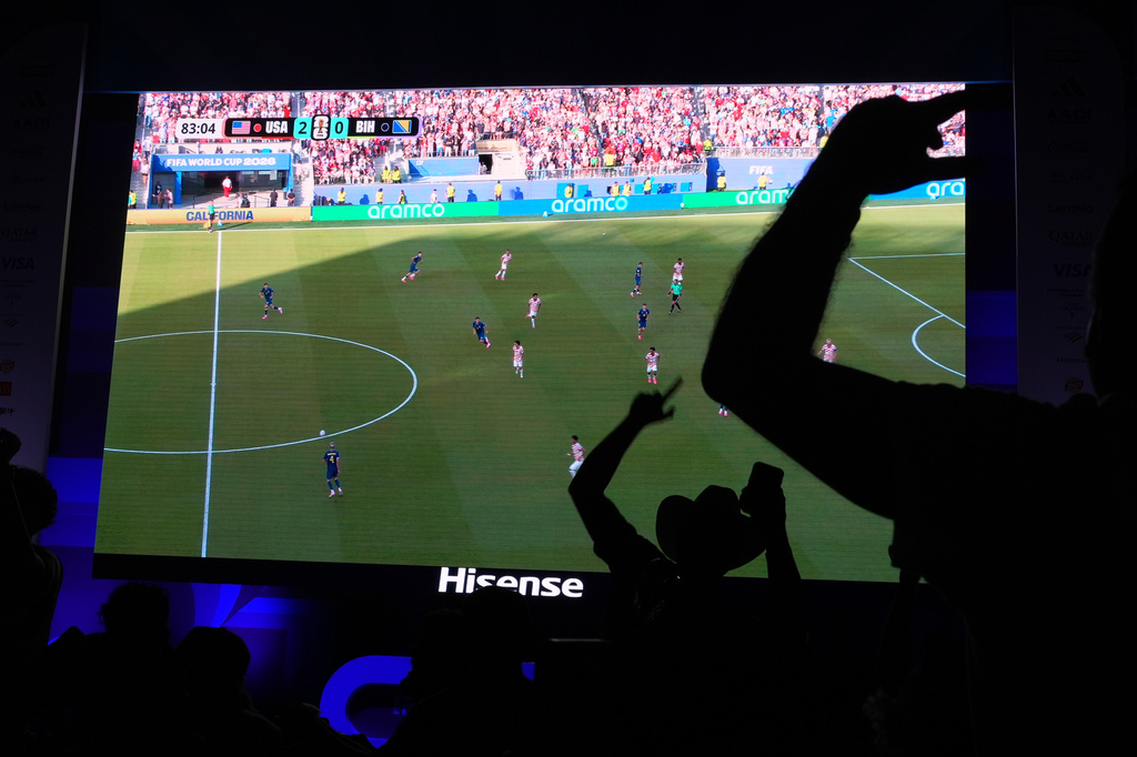 Soccer fans, including Caleb Triana, wearing a cowboy hat, celebrate the U.S. scoring its second goal as they watch a live broadcast of the World Cup round of 32 soccer match between the United States and Bosnia, Wednesday, July 1, 2026, at an official fan fest in downtown Miami. (AP Photo/Rebecca Blackwell)