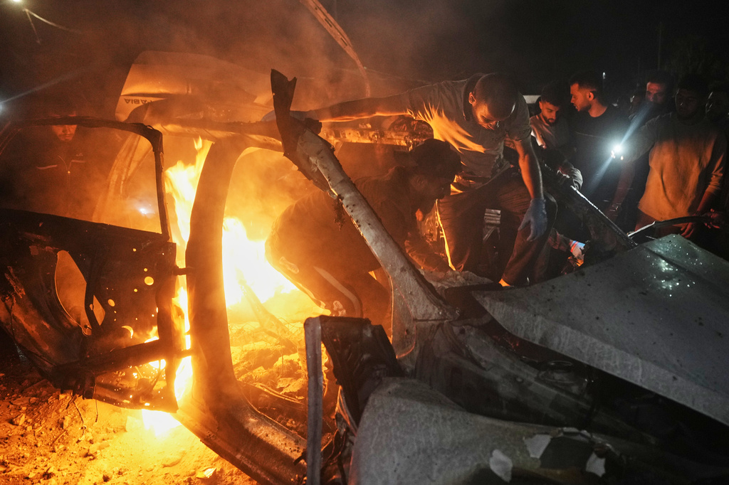 Palestinians search inside a burning vehicle following an Israeli strike in Gaza City, Friday, May 15, 2026. (AP Photo/Jehad Alshrafi)