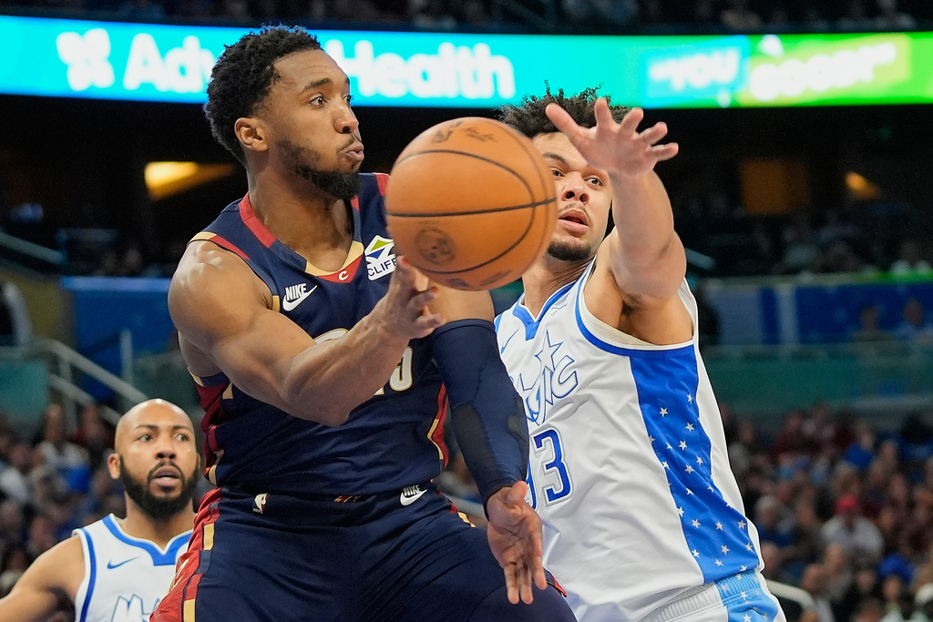 Cleveland Cavaliers guard Donovan Mitchell, left, passes the ball past Orlando Magic forward Noah Penda during the second half of an NBA basketball game, Wednesday, March 11, 2026, in Orlando, Fla. (AP Photo/John Raoux)