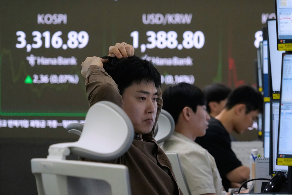 A currency trader watches monitors near a screen showing the Korea Composite Stock Price Index (KOSPI), top left, and the foreign exchange rate between U.S. dollar and South Korean won at the foreign exchange dealing room of the Hana Bank headquarters in Seoul, South Korea, Thursday, Sept. 11, 2025. (AP Photo/Ahn Young-joon)
