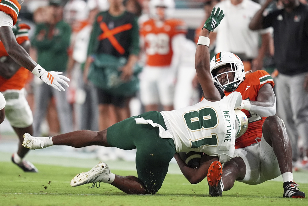 Miami linebacker Chase Smith brings down South Florida wide receiver Christian Neptune during the first half of an NCAA college football game, Saturday, Sept. 13, 2025, in Miami Gardens, Fla. (AP Photo/Rebecca Blackwell)