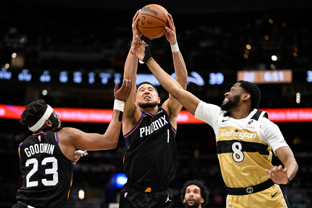 Phoenix Suns guard Devin Booker (1) intercepts a pass intended for Washington Wizards guard Malaki Branham (8) during the first half of an NBA basketball game, Monday, Dec. 29, 2025, in Washington. (AP Photo/John McDonnell)