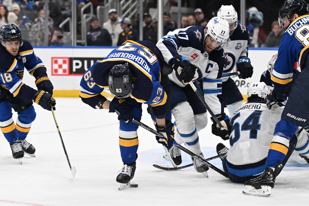 St. Louis Blues left wing Jake Neighbours (63), left, battles Winnipeg Jets center Adam Lowry (17) for the puck during the second period of an NHL hockey game on Wednesday, Dec. 17, 2025, in St. Louis. (AP Photo/Joe Puetz)