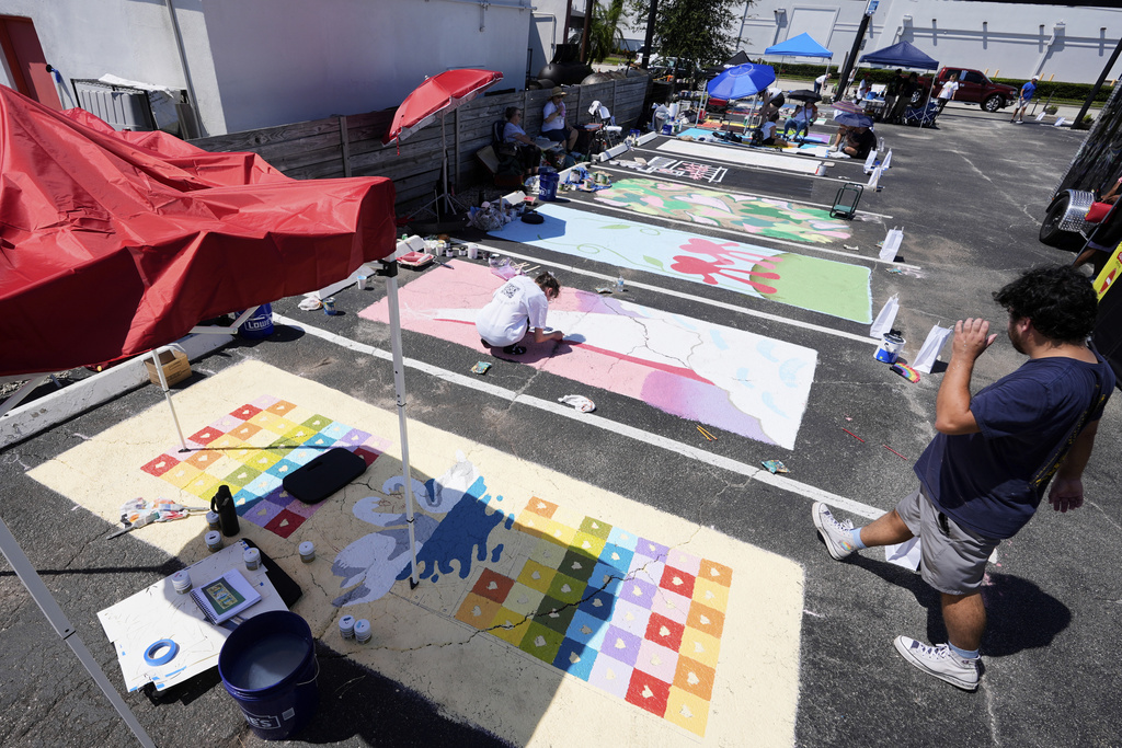 Artists paint parking spaces at a local restaurant to support the LBGTQ+ community and to protest state mandates on crosswalk art Monday, Sept. 15, 2025, in Orlando, Fla. (AP Photo/John Raoux)