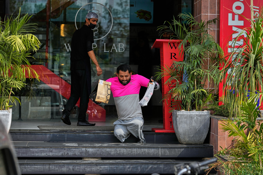 Hamza Ali, 28, who lost both legs in a road accident, leaves after collecting a meal order for delivery in Islamabad, Pakistan, Friday, July 17, 2026. (AP Photo/Anjum Naveed)
