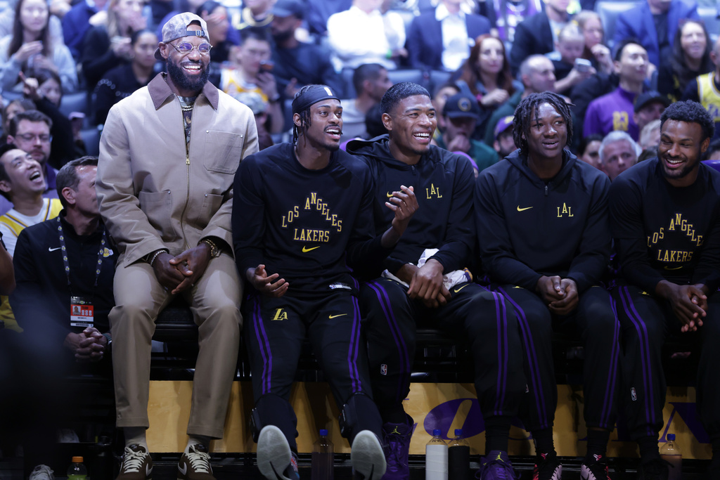 Los Angeles Lakers forward LeBron James (23), left, smiles from the bench during the second half of an NBA basketball game against the Minnesota Timberwolves, Tuesday, March 10, 2026, in Los Angeles. (AP Photo/Ethan Swope)