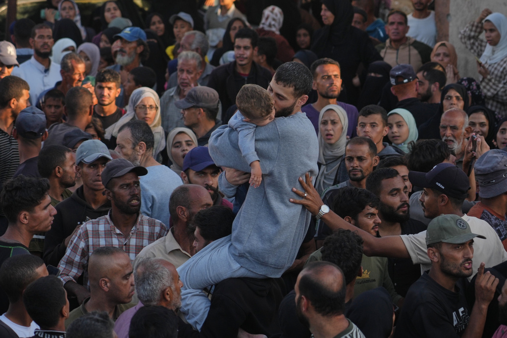 A freed Palestinian prisoner, center, hugs a child as he is greeted upon arriving in the Gaza Strip after being released from Israeli jails under a ceasefire agreement between Hamas and Israel, in Khan Younis, southern Gaza Strip, Monday, Oct. 13, 2025. (AP Photo/Jehad Alshrafi)