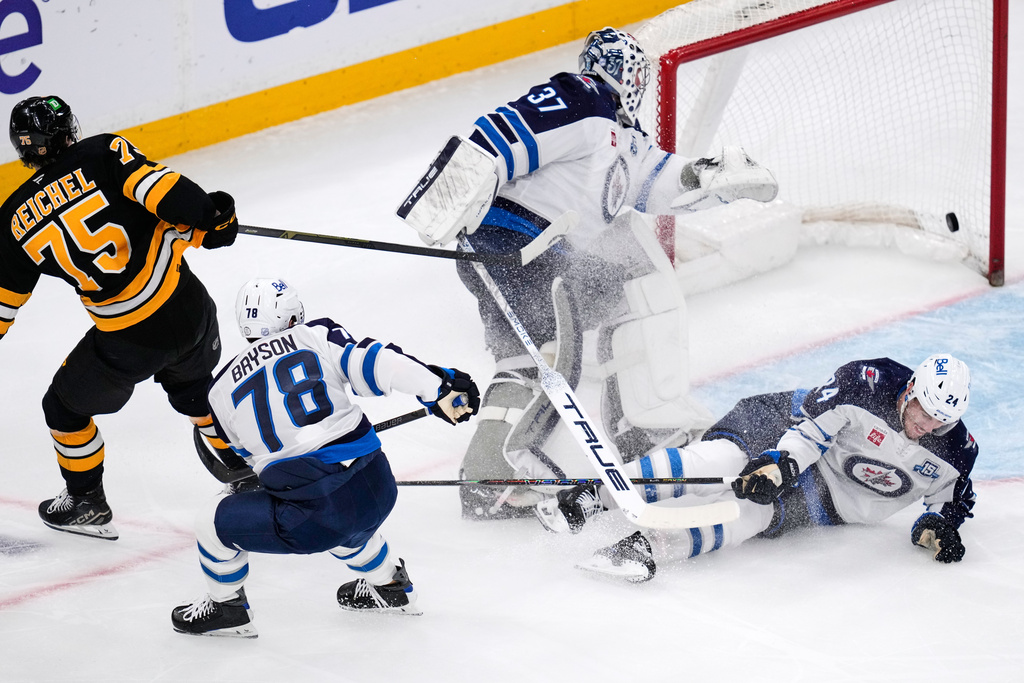 Boston Bruins left wing Lukas Reichel (75) shoots the puck past Winnipeg Jets goaltender Connor Hellebuyck (37) for a goal during the second period of an NHL hockey game, Thursday, March 19, 2026, in Boston. (AP Photo/Charles Krupa)