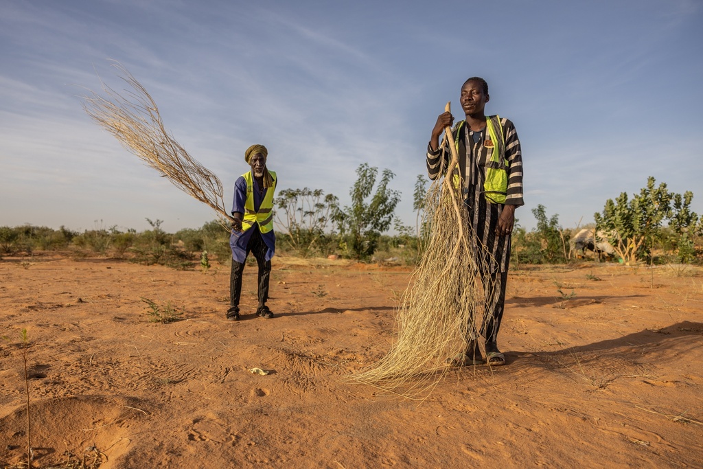 Mbera fire brigade members from the NGO SOS desert demonstrate the brushing technique used to extinguish fires in Mbera Refugee Camp, near Bassikounou, Hodh El Chargui Region, Mauritania, Saturday Nov. 8, 2025. (AP Photo/Caitlin Kelly)
