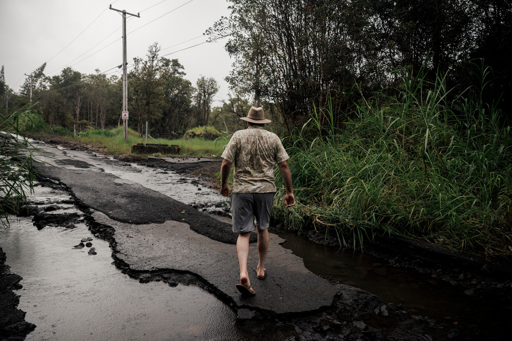 Eric Hubner walks along a washed-out road near his home in Mountain View, Hawaii, Sunday, Aug. 16, 2026, after a severe weather system went through the area. (Stephen Lam/San Francisco Chronicle via AP)