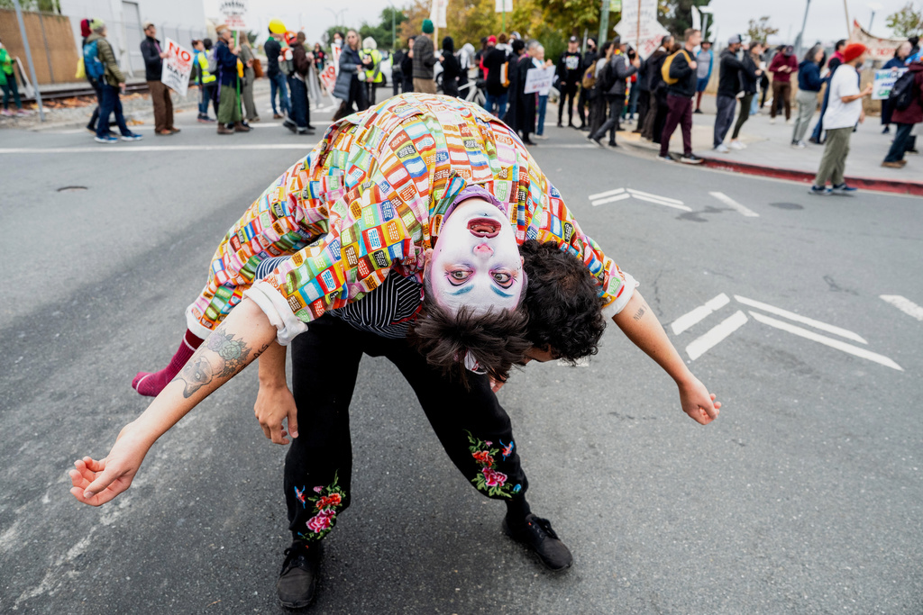 A performer, Clown Kendra Ferguson, joins protesters blocking the entrance to Coast Guard Base Alameda shortly after a caravan of U.S. Customs and Border Protection personnel arrived on Thursday, Oct. 23, 2025, in Oakland, Calif. (AP Photo/Noah Berger)